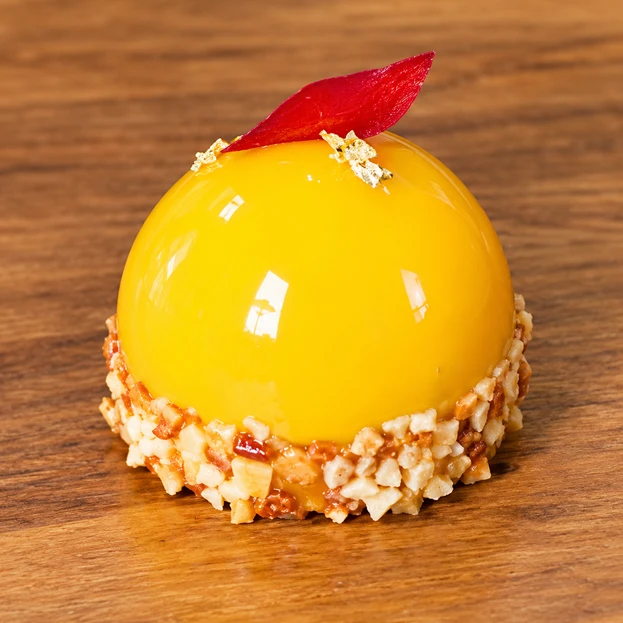 Entremet glace a la mangue, eclats de praline et feuille de fruit rouge