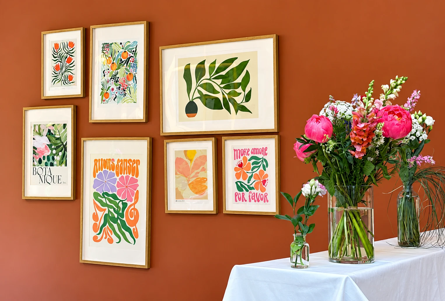 Mur de cadres et bouquets de saison dans la salle