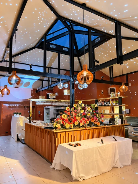 La salle sous son plafond etoile, bar en bois et grande composition florale