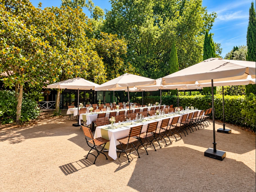 La terrasse des Magnolias, longues tables dressees sous les parasols dans le jardin
